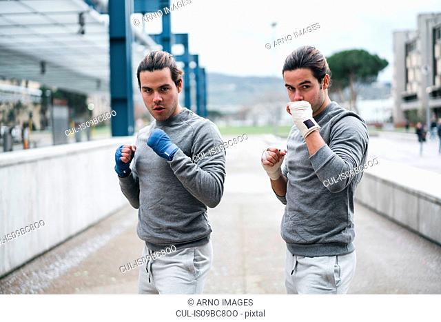 Identical male adult twin boxers training outdoors, fighting stance portrait