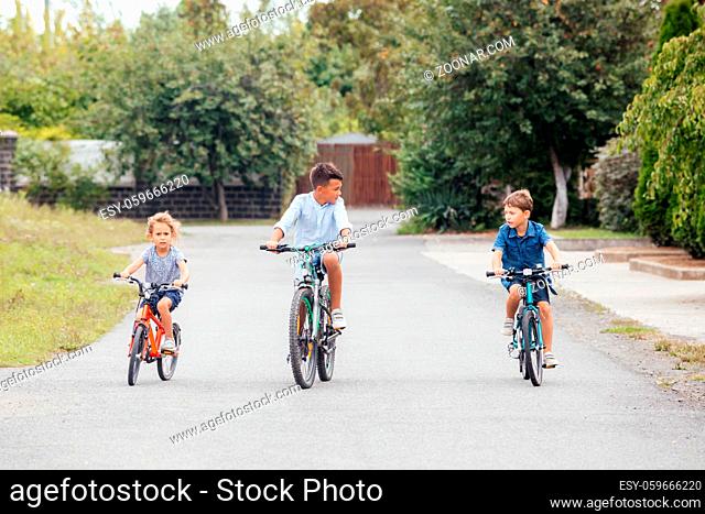 Kids have a leisure on bicycles outoodrs at the street. The friends ride bicycles around the area