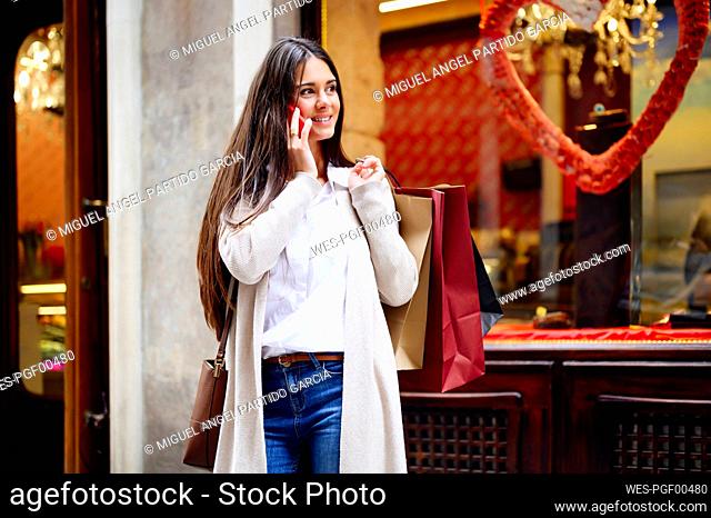 Smiling beautiful woman talking on smart phone while looking away