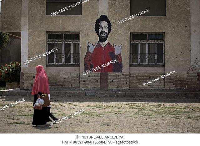 dpatop - A picture made available on 21 May shows an Egyptian woman walking past a graffiti of Liverpool's Mohamed Salah