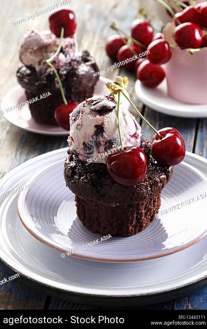 Chocolate muffin served with a scoop of ice cream and cherries
