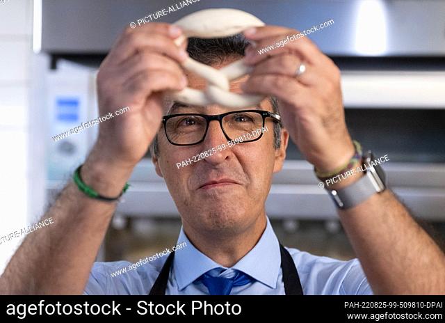 25 August 2022, Baden-Wuerttemberg, Bad Urach: Federal Minister of Food Cem Özdemir (Bündnis 90/Die Grünen) looks at a pretzel during a visit to a branch of the...