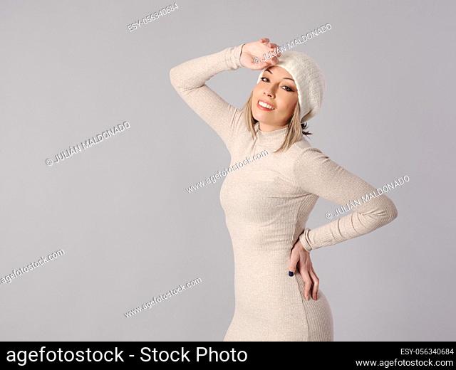 Pretty young woman poses in tight dress and hat with cheerful fitness