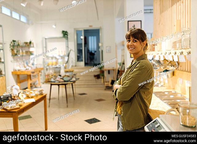 Smiling female owner with arms crossed standing in cafe
