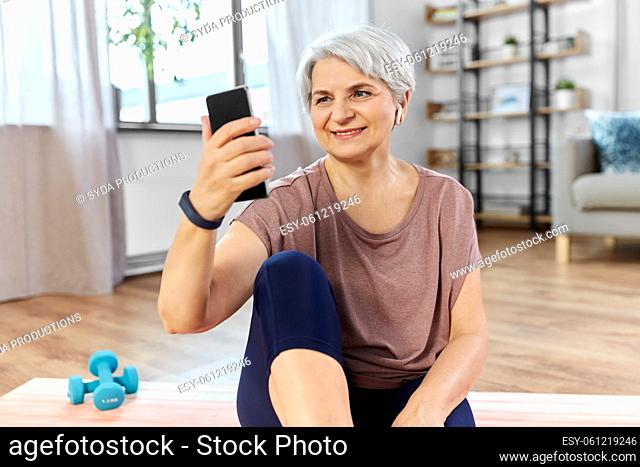 woman with phone and earphones exercising at home