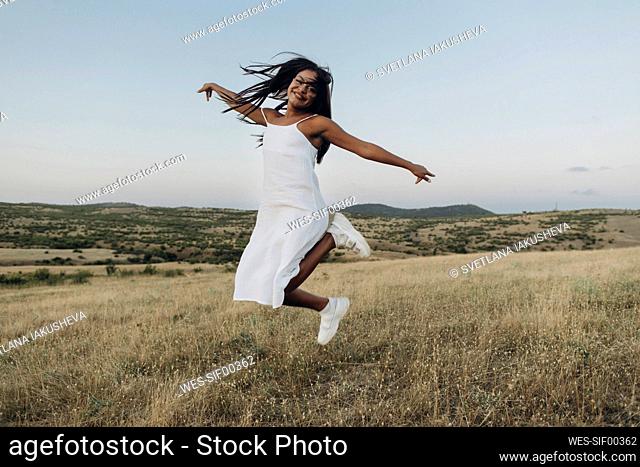 Carefree woman jumping in meadow