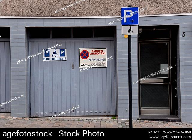 23 May 2021, North Rhine-Westphalia, Cologne: Signs on a garage: handicapped parking no stopping keep driveway clear. Photo: Horst Galuschka/dpa