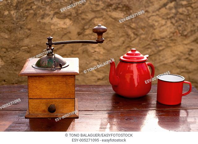 retro old coffee grinder with vintage teapot and red cup