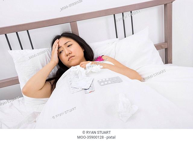Woman suffering from headache and cold lying in bed