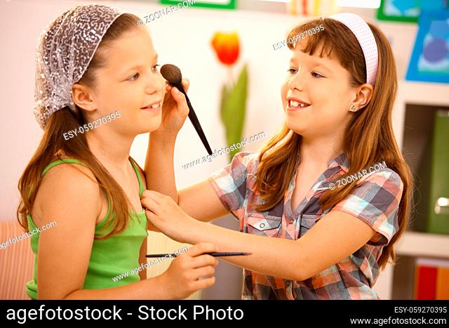 Little girl friends having fun with makeup at home, smiling