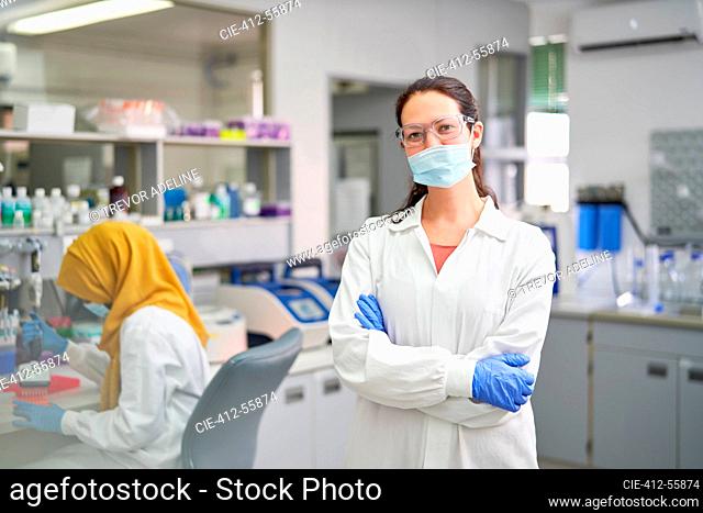 Portrait confident female scientist in face mask and rubber gloves