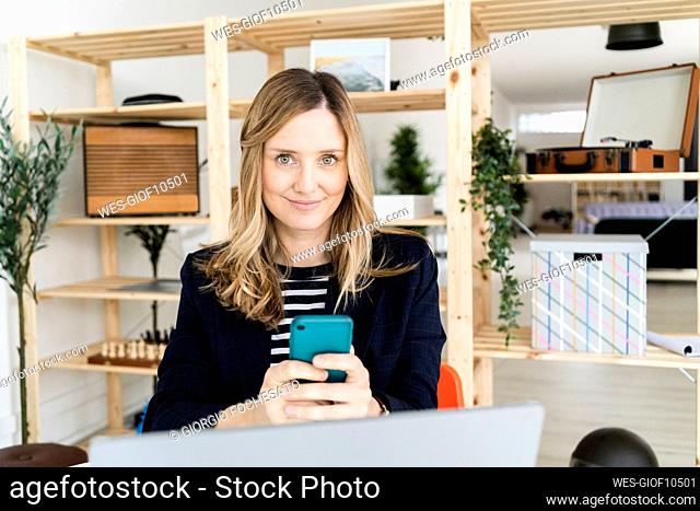 Portrait of smiling business woman using smart phone in office