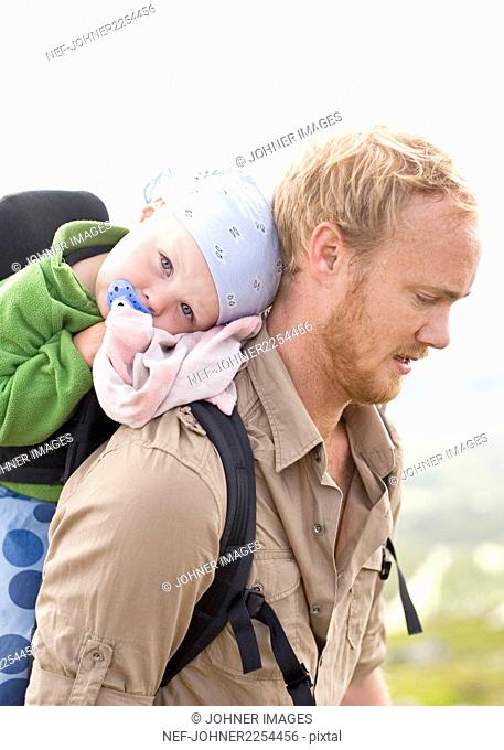 Father hiking with daughter in baby carrier