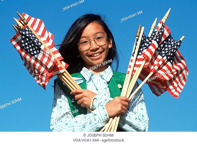 Filipino Girl Scout holding armful of American flags, Los Angeles, California
