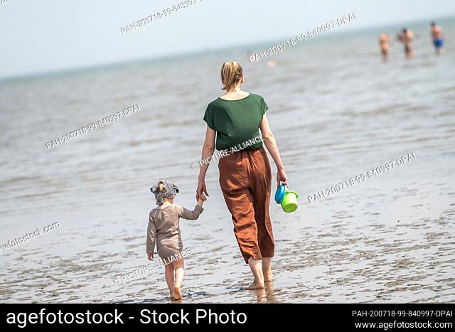 18 July 2020, Lower Saxony, Schillig: A beach visitor is with her daughter on the North Sea beach of Schillig in summery temperatures