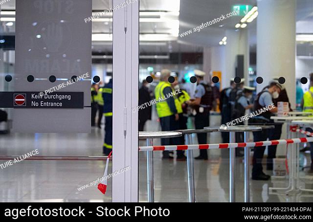 01 December 2021, Bavaria, Munich: Employees of the Bavarian State Office for Health and Food Safety (LGL) and police officers stand in the arrivals area at...