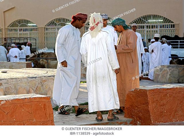 Local men wearing Dishdasha, the traditional Omani garment, on the grounds of the goat market, Nizwa, Sultanate of Oman