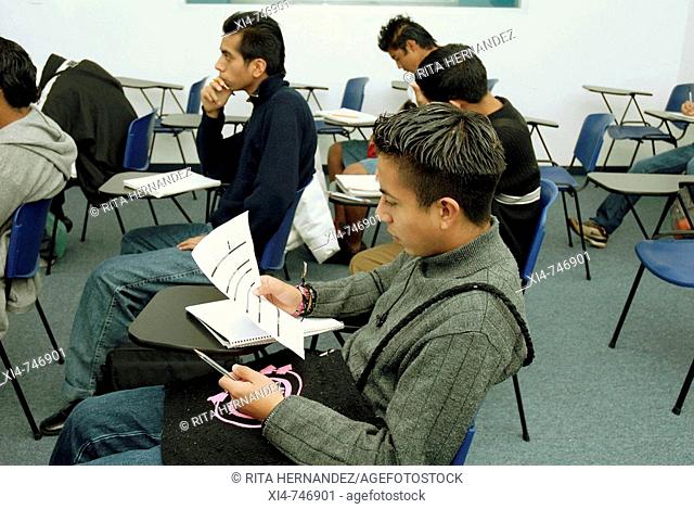 Male in the  classroom, reading some paper. Mexico