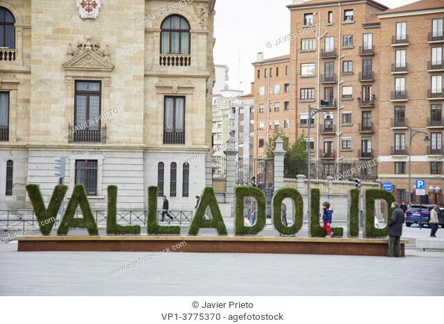 The name of the city of Valladolid written on a poster with plant letters appears in front of the façade of the Academia de Caballería, in the Zorrilla square
