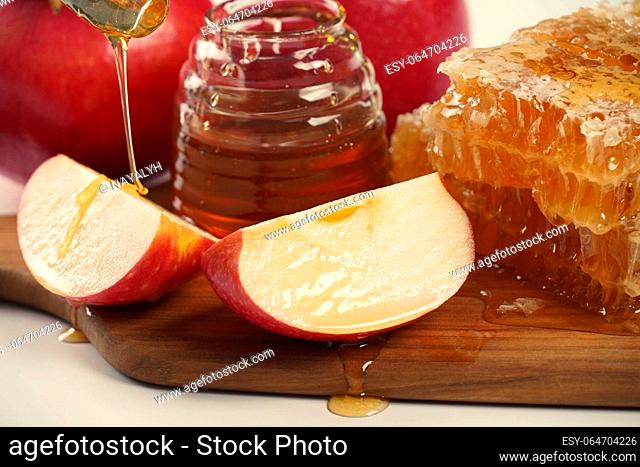Jewish holiday Rosh Hashana celebration. Pomegranate, apples and honey traditional products for the holyday. Pouring honey on apple and pomegranate