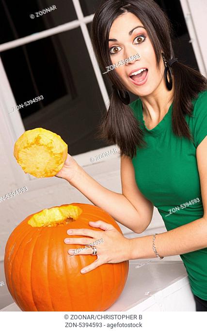 Pretty housewife cuts the top off a pumpkin getting it ready to carve