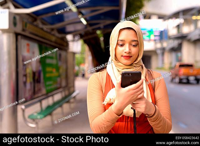 Portrait of young beautiful Indian Muslim woman with hijab at the bus stop in the city