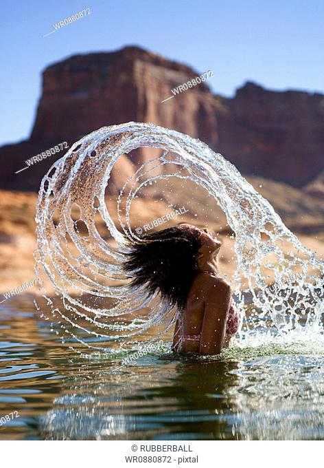 Young woman tossing her wet hair in a lake