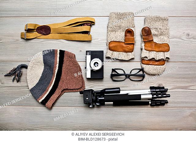 Photographer's equipment and clothing items arranged on floor