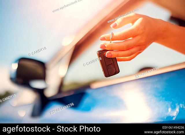 Woman's hand holding key from her new car. Concept of buying and selling ofthe automobile