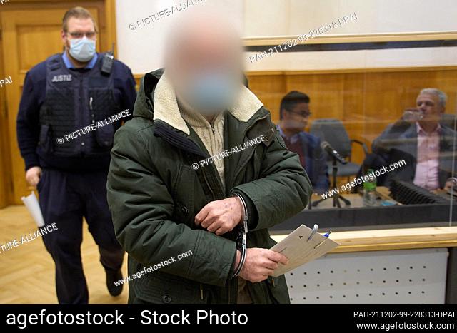 02 December 2021, Rhineland-Palatinate, Koblenz: The defendant is led into the courtroom of the Higher Regional Court in handcuffs