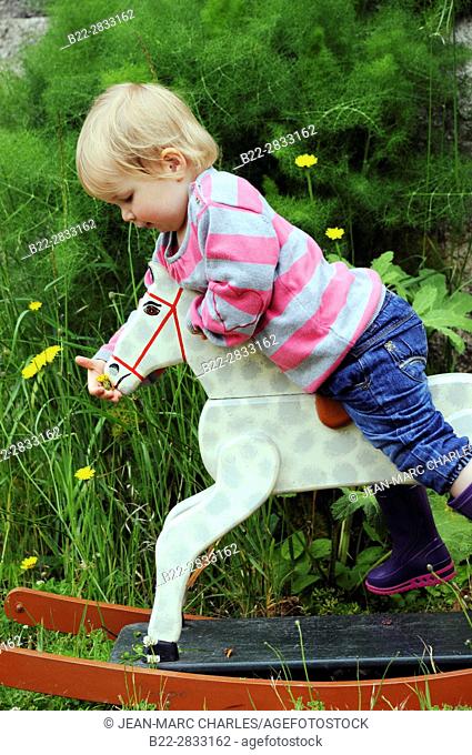 2 years old girl playing with a wooden horse