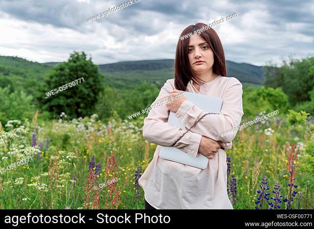 Freelancer chained to laptop in meadow