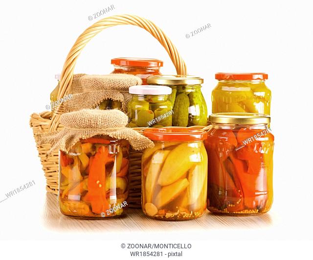 Composition with wicker basket and jars of pickled vegetables. Marinated food