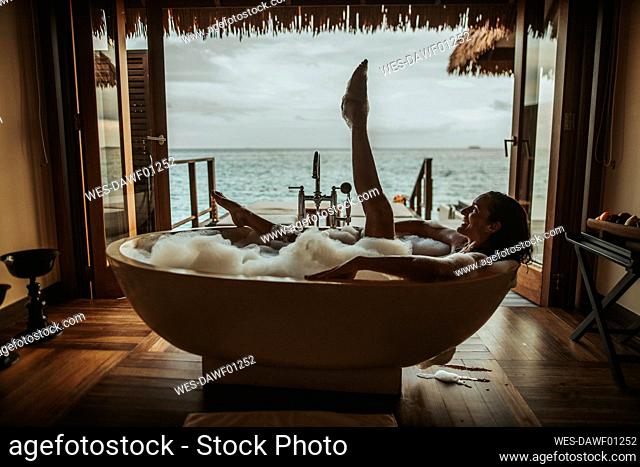 Woman relaxing in bathtub with view to the sea, Maguhdhuvaa Island, Gaafu Dhaalu Atoll, Maldives
