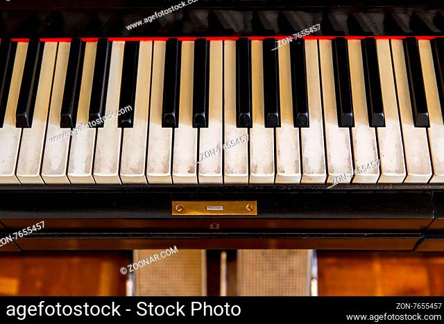 Close up front view of black old piano with white keys on
