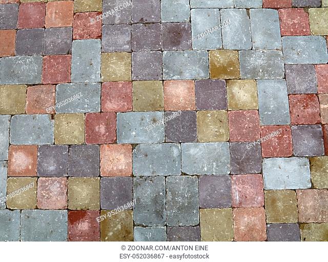Background of street road colorful stone paving of multicolor bricks, close up, high angle view