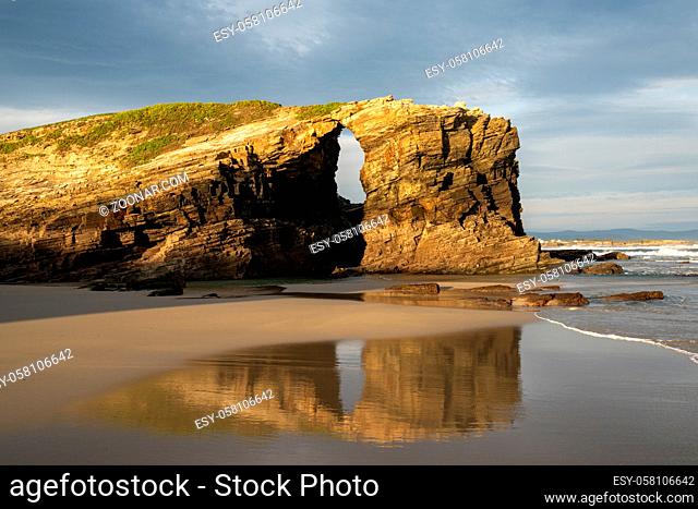 A beautiful beach with fine sand and rocky cliffs at sunrise