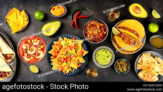 A panorama of Mexican food, many dishes of the cuisine of Mexico, flat lay, overhead shot on a black background. Nachos, guacamole, shrimp cocktail, tacos