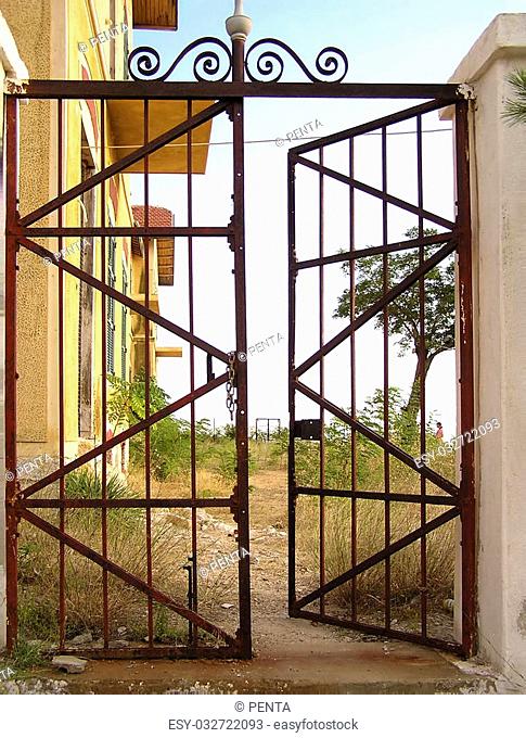 Old rusted metal gate at abandoned estate, partly opened
