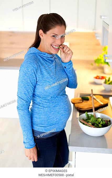 Pregnant woman preparing fresh salad in the kitchen