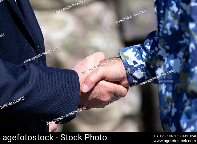 05 September 2023, Schleswig-Holstein, Panker: The representative of a defense contractor (l) shakes hands with an officer in camouflage fatigues (r)