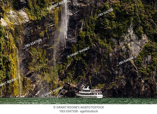 A Milford Sound Cruise Boat Under A Waterfall, Fiordland National Park, South Island, New Zealand