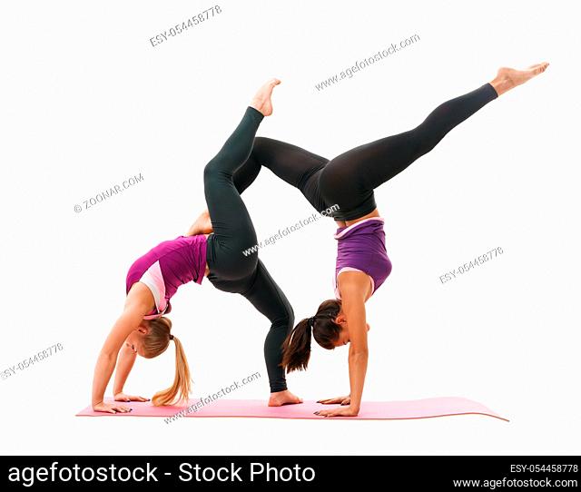 Slim pretty girls in violet tops and black leggings doing handstand in studio