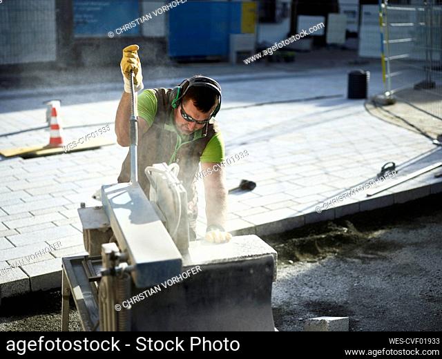 Craftsperson cutting paving stone on industrial equipment