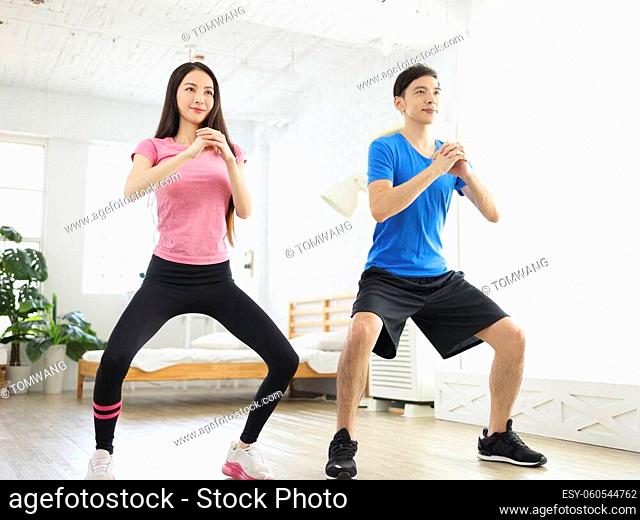 Young couple doing squats together at home during quarantine