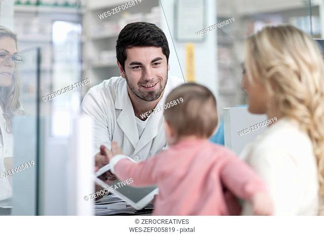 Pharmacists assisting mother with child at dispensary