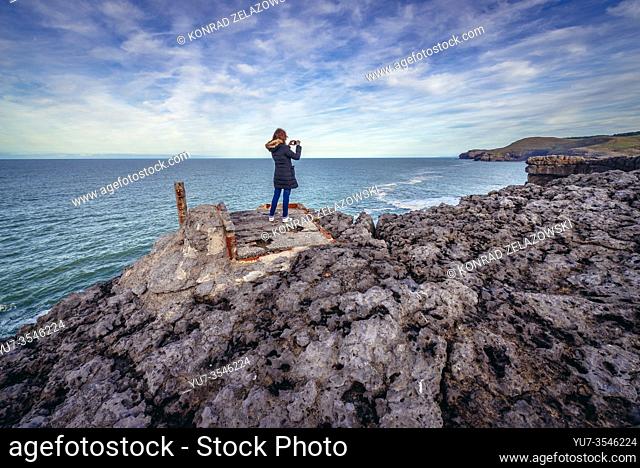 Tourist on Cabo Ajo - cape with famous Ojerada cave on the coast of Biscay Bay near Ajo town in Bareyo municipality, Cantabria region of Spain