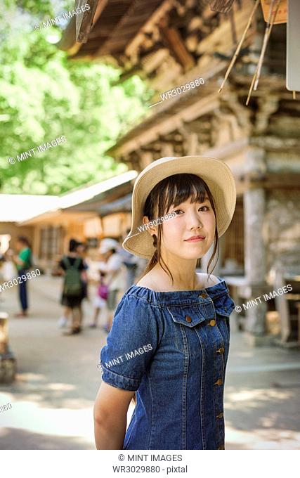 Young woman wearing blue dress and hat at Shinto Sakurai Shrine, Fukuoka, Japan