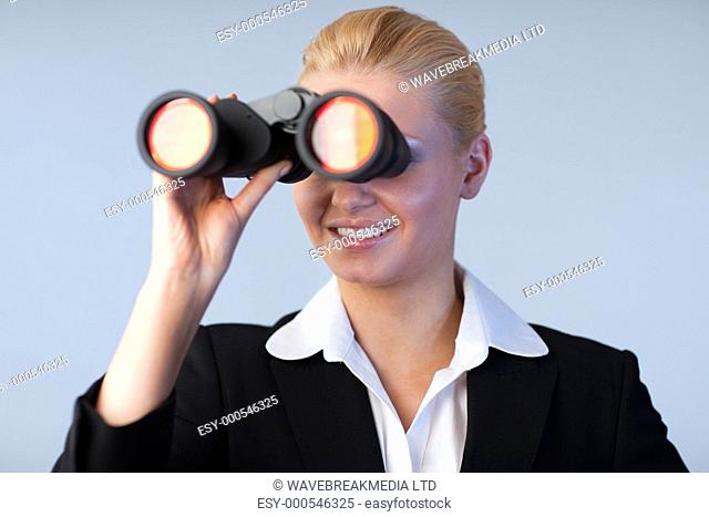 Happy business woman looking outwards thorugh binoculars Focus is on the Person