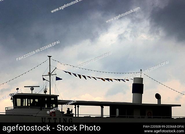 08 May 2022, Bavaria, Schondorf: A passenger of the excursion steamer ""Diessen"" takes a photo on the Ammersee under a cloudy sky